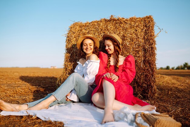 Two young women having fun near haystack Fashion concept Summer concept