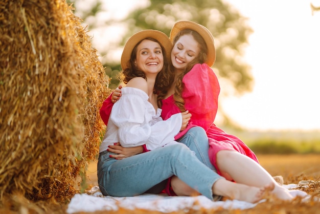 Two young women having fun near haystack Fashion concept Summer concept