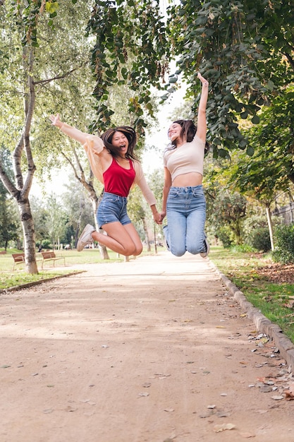 손을 잡고 기쁨으로 점프 두 젊은 여성