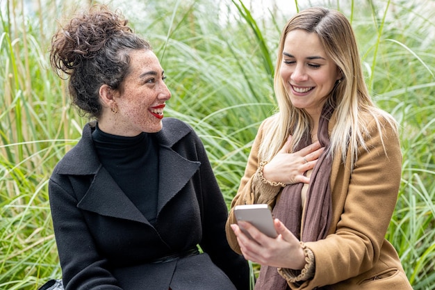 Two young women looking at smartphone pretty woman using cellphone and having fun friends and social network concept