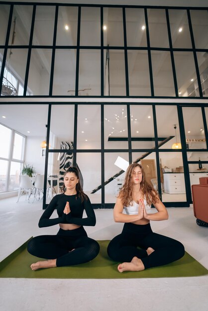 Фото Две молодые женщины медитируют в позе лотоса с руками в намасте