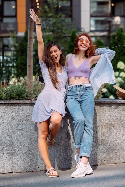 Two young women pose against the background of a building