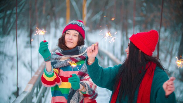 Two young women standing on the bridge holding sparklers and having fun