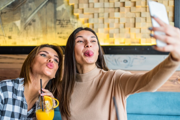 Photo two young women taking selfie in cafe