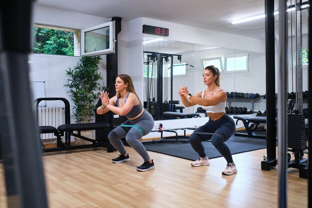 Two young women training their gluteus muscles with elastic
bands in a gym