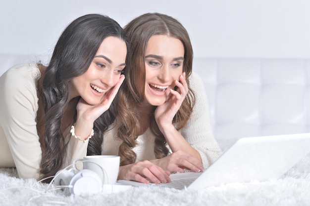 Two young women using laptop and smiling
