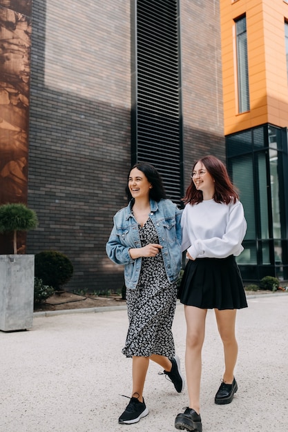 Two young women walking down the street chatting and laughing