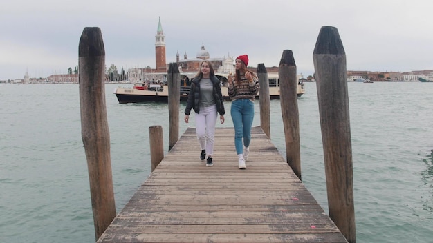 Two young women walking on the pier One of them eating icecream