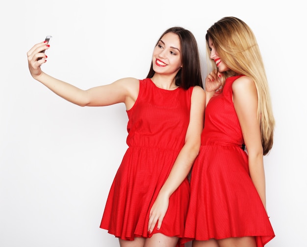 셀카를 찍고 빨간 드레스를 입고 두 젊은 여성