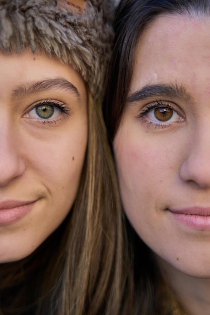 Two young women with their faces together Half of a couple39s face looking at the camera