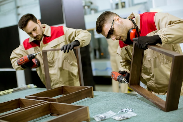 Due giovani operai che montano mobili in fabbrica