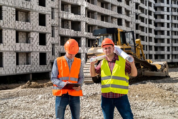 Two young workers in uniforms discuss the process of building a house