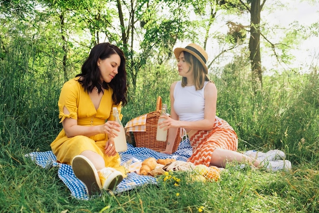 Foto due giovani donne che abbracciano la natura fanno un picnic sulla coperta blu