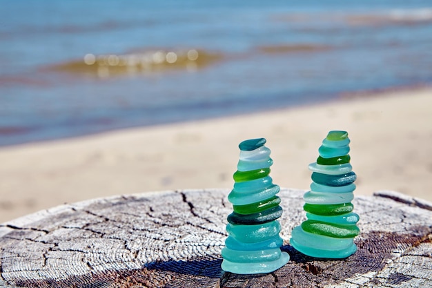 Two zen pyramids of blue and green glass stones on wooden surface against background of coastal sea