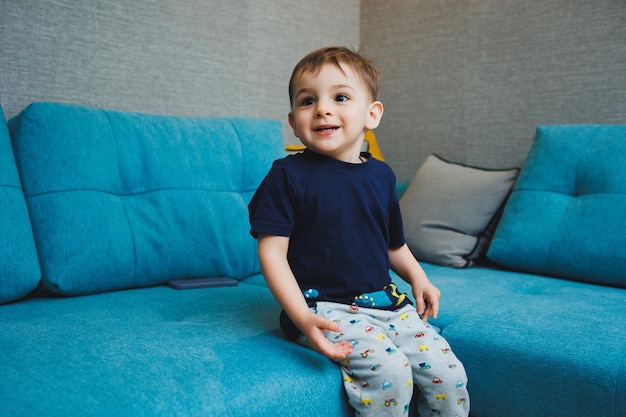 Twoyearold little boy sitting on the sofa at home home entertainment of a small child