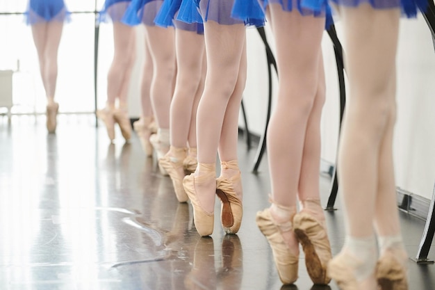 Завязывая тапочки перед выступлением Молодая балерина в белой пачке завязывает тапочки сидя
