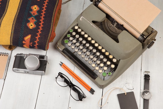 Typewriter notepad camera clothes glasses and watch on wooden background