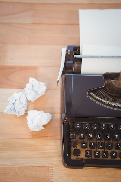 Typewriter with crumpled paper on table in office