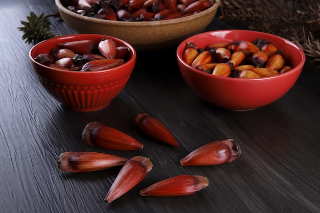 Typical araucaria seeds used as a condiment in Brazilian cuisine in winter. Brazilian pinion nuts in brown and red wooden bowl on gray wooden background.