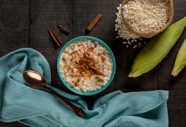 Piatto tipico brasiliano hominy canjica con cannella in vaso blu in vista dall'alto di legno scuro.