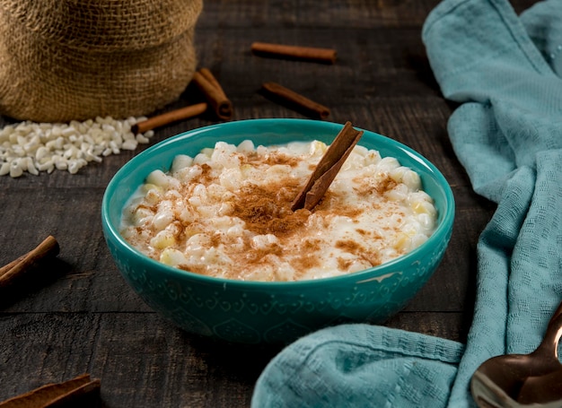 Typical brazilian dish hominy canjica with cinnamon in blue pot in dark wood.