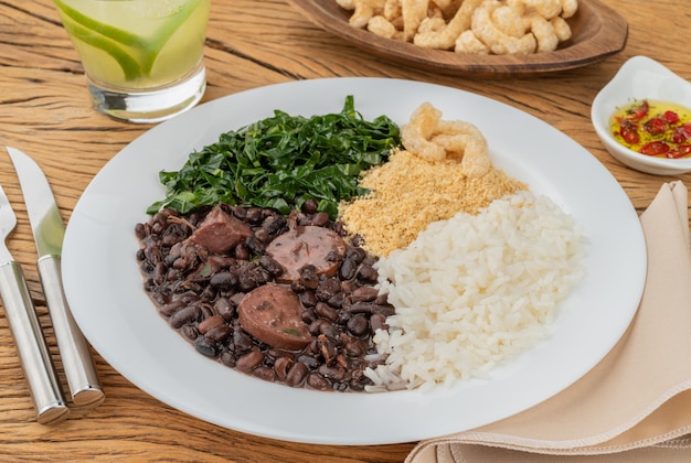 Typical brazilian feijoada with rice pepper farofa kale caipirinha and cracklings