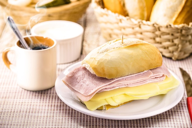 モッツァレラチーズとハムのフランスのパンのスライスとホットコーヒーの朝食のための典型的なブラジルのスナックパオデサル