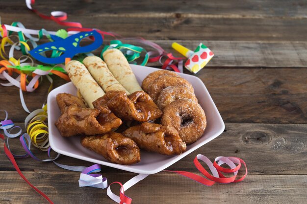 Typical carnival desserts with carnival decorations on a wooden background. Copy space.