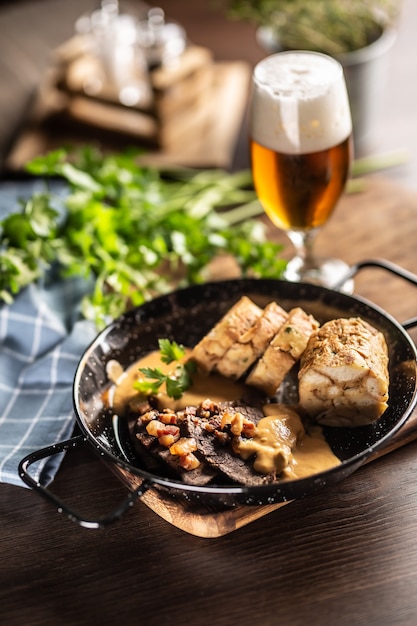 Photo typical czech food svickova na smetane with dumplings and a draft pilsener beer in a glass.