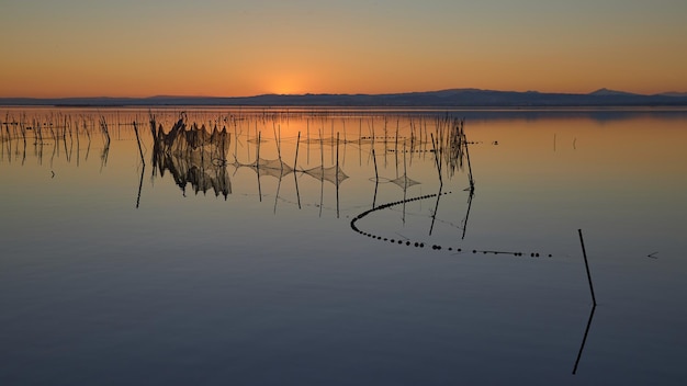 Tipico sistema di pesca con canne e bastoni, della laguna di valencia in spagna. cielo al tramonto