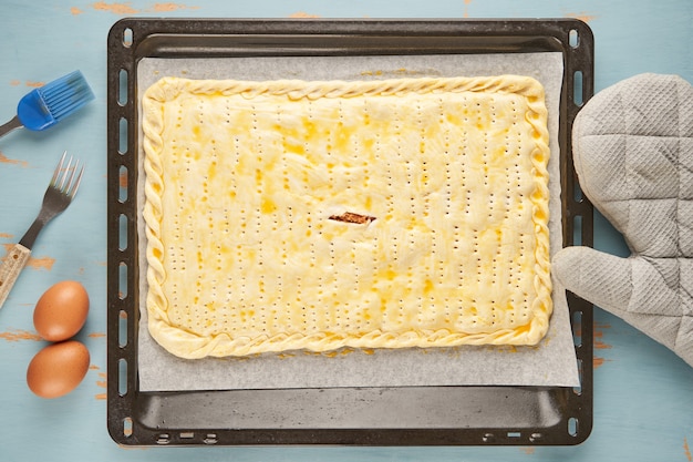 Typical Galician raw empanada stuffed with tuna is on a baking tray