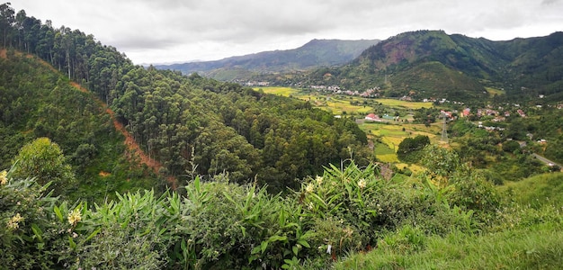 Typical Madagascar landscape at Mandraka region. Hills covered with green foliage, small villages in distance, on overcast day.