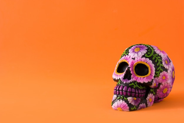 Typical Mexican skull with flowers painted on orange.