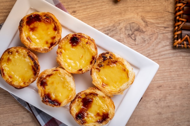 Typical Portuguese custard pies . traditional portuguese pastry. On a wooden table.