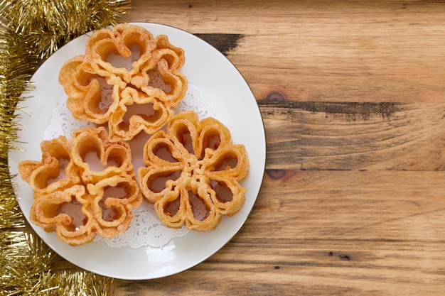 Typical portuguese dessert filhos on white plate on brown wooden surface