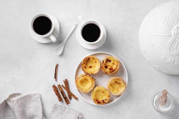 Typical portuguese egg tart pastel de nata with cups of coffee on concrete background top view