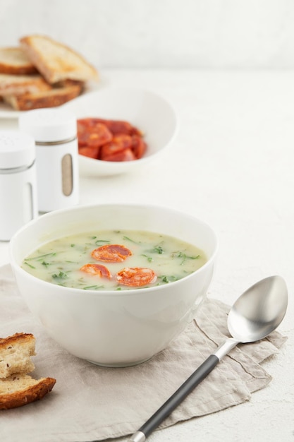 Photo typical portuguese soup caldo verde with bread and chorizo sausage on white background