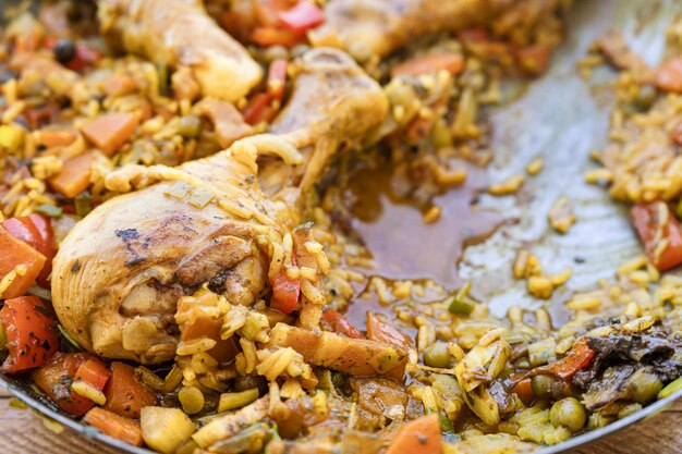 Typical Spanish food of Arroz con pollo or chicken paella. Close-up of the chicken leg with the rice inside the paella pan. Ethnic or regional food concept.