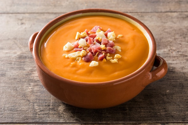 Typical Spanish salmorejo cream with ham and egg on wooden table