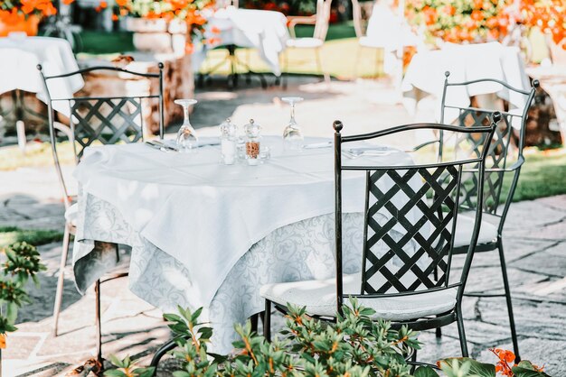 Типичный столик ресторана на террасе в романтическом роскошном городке Аскона на озере Маджоре, кантон Тичино, Швейцария. Дорогой семейный завтрак и ужин в уличных кафе и барах в Швейцарии летом. Веранда