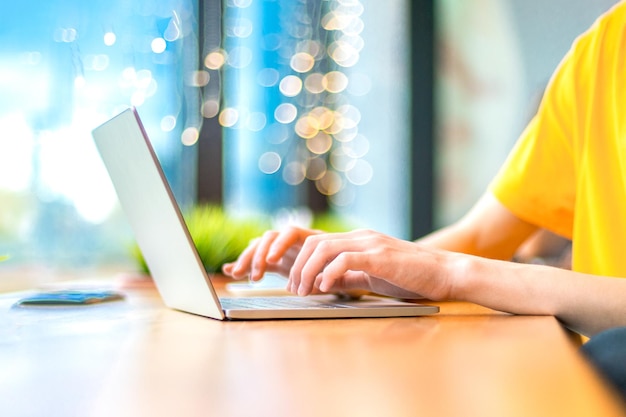 Typing hands of guy sitting at a table by the window