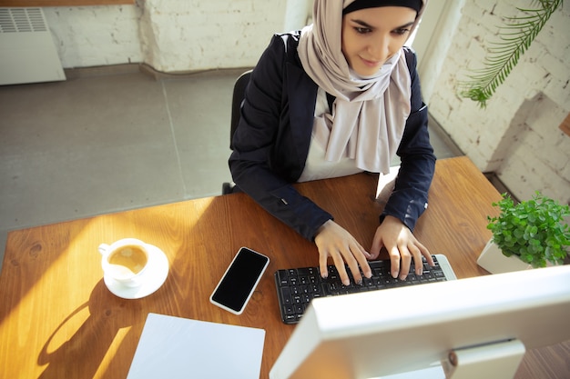 텍스트를 입력합니다. 오픈스페이스나 사무실에서 일하는 동안 히잡을 쓴 아름다운 아라비아 여성 사업가의 초상화. 직업의 개념, 비즈니스 영역의 자유, 리더십, 성공, 현대적인 솔루션.
