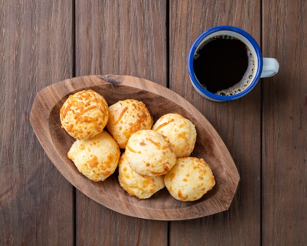 Typisch Braziliaans kaasbroodje in een bord met koffie over houten tafel