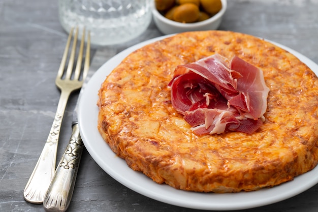 Typisch Spaans voedsel Tortilla met gerookt vlees en aardappel op witte schotel