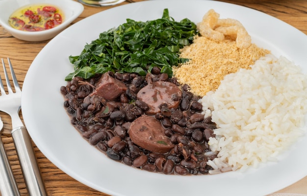 Typische braziliaanse feijoada met rijstpeper, farofa boerenkool en cracklings