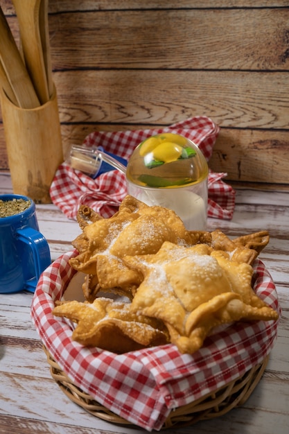 Typische gebakken zoete aardappel en kweepeer gebak op een dienblad vergezeld van de klassieke mate op een oude houten tafel. etnisch of regionaal keukenconcept. verticale oriëntatie.