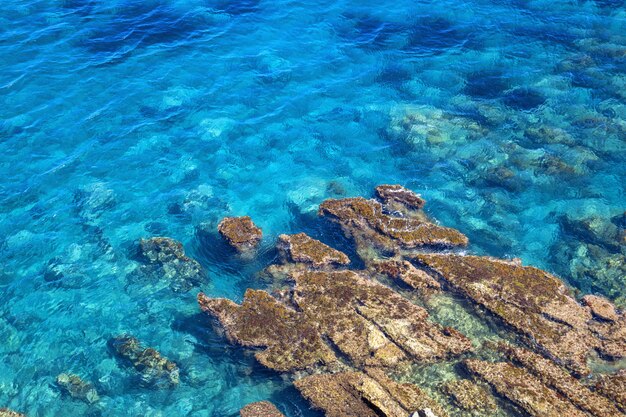 Tyrrhenian coast in Sicily, Cefalu. Bright blue deep sea with big stone in water.