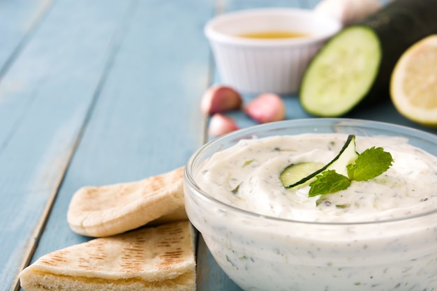 Tzatziki and ingredients on blue wooden table