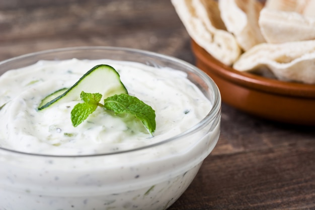 Tzatziki sauce in bowl on rustic wooden table close up