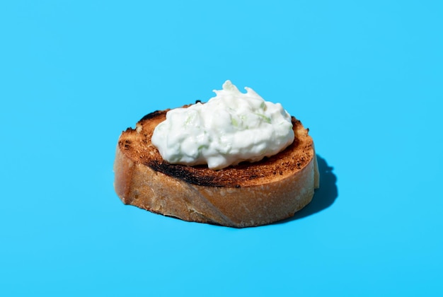 Tzatziki on toasted bread isolated on a blue background